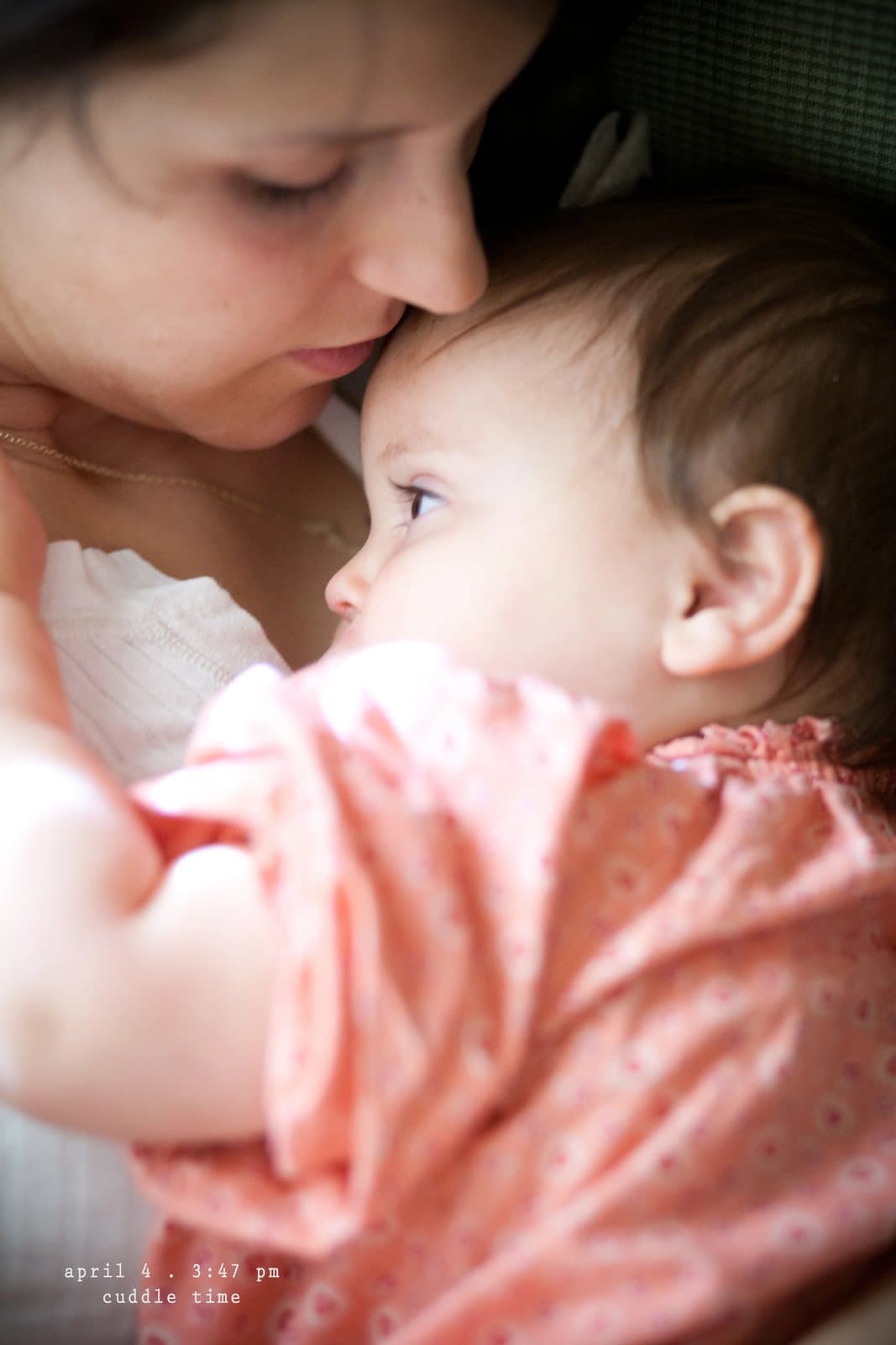 A woman nuzzles a baby in a pink dress close to her face, captioned cuddle time.