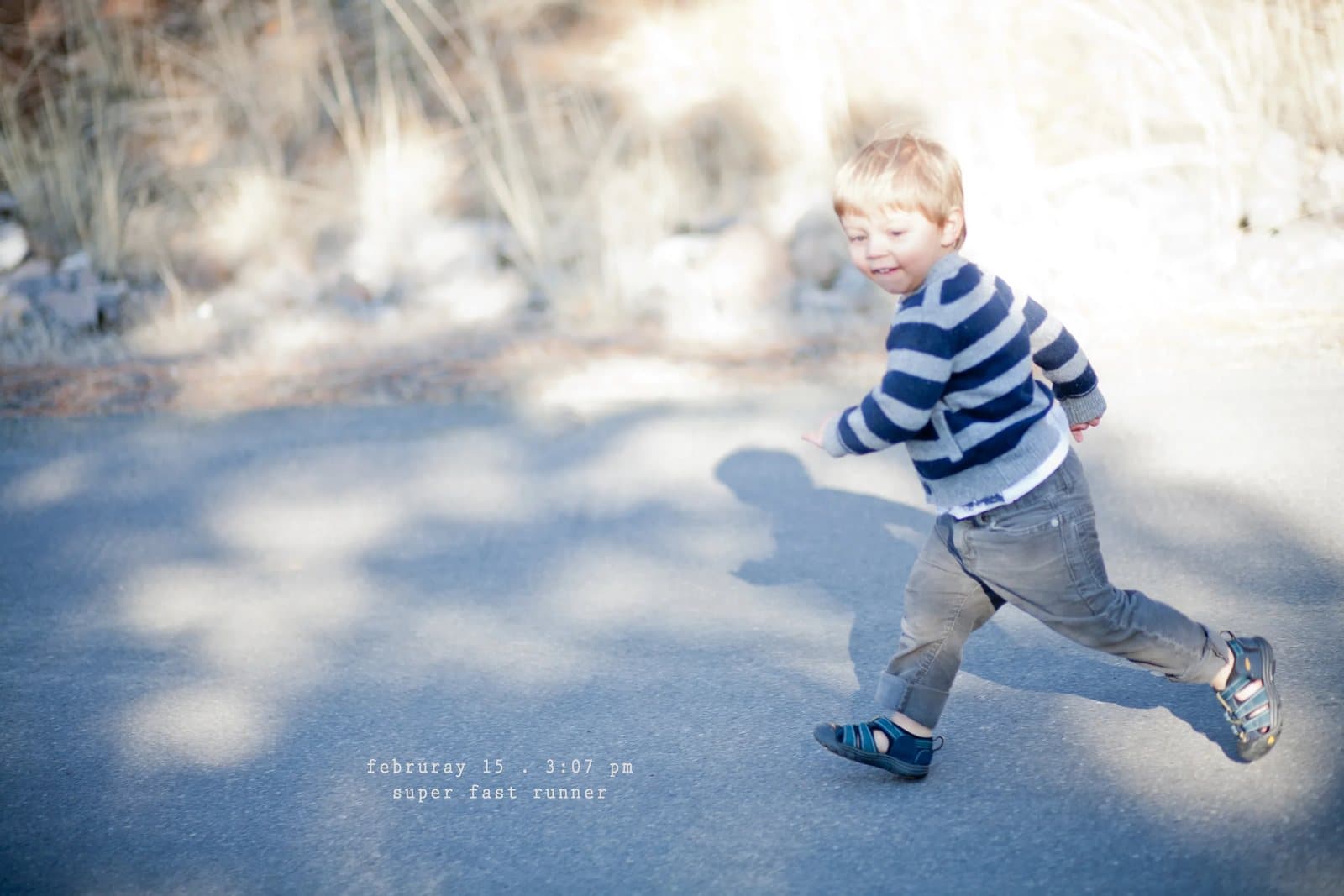 A toddler in a striped sweater runs along a sunny road, captioned super fast runner.