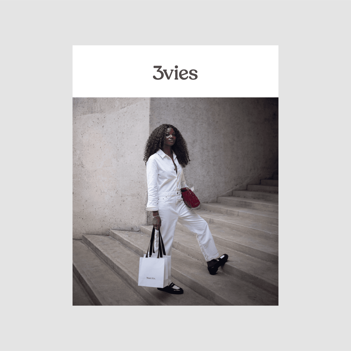 Cover of 3vies Volume 38, a woman in a white jumpsuit with a red bag on concrete steps.