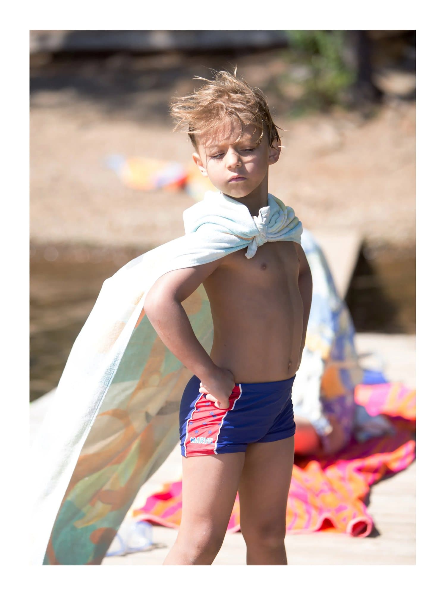 Pax wearing a towel as a cape, hands on hips on a dock, TIMELESS print Pax.